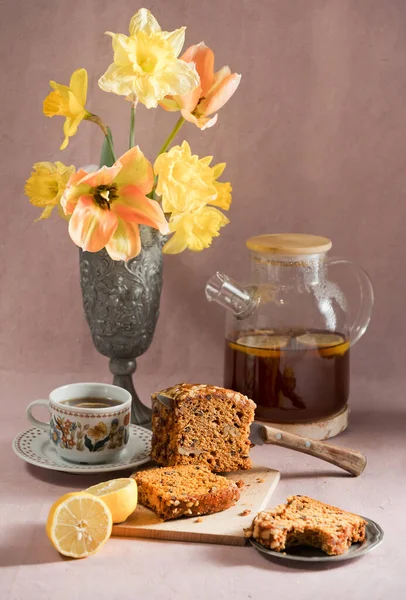 Still life, concept of early spring breakfast with coffee or tea and cupcake on the background of a bouquet of tulips and daffodils — Stock Photo, Image