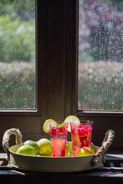 Malinová limonáda na parapetu, venku z okna déšť a slunce — Stock fotografie