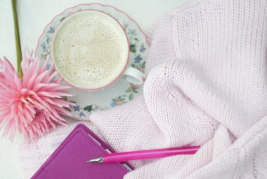 workplace for a young girl on a light background, pink dahlia, a cup of cappuccino, a diary with a pen, spring pink lifestyle concept, morning mood