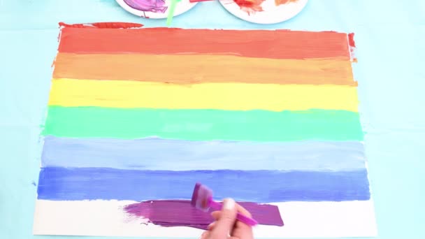 Close-up van een vrouw die met de hand een regenboog op papier tekent als symbool van lgbt minderheden — Stockvideo