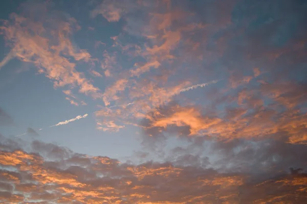 Vainilla puesta del sol, nubes suavemente rosadas sobre el fondo del cielo puesta del sol y el rastro de un avión en el cielo, textura, — Foto de Stock