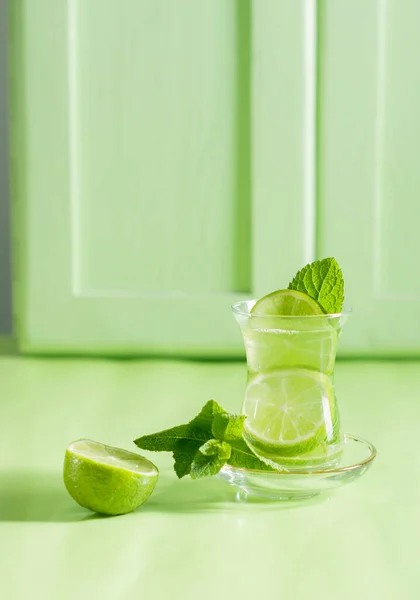 Čaj s mátou a vápnem, s uklidňujícím účinkem, zelená zátiší zblízka na zeleném pozadí, horní pohled. mojito, nápoj na zdraví, alternativní medicína — Stock fotografie