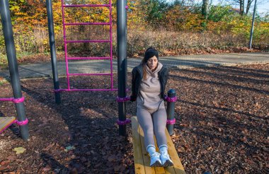 Açık hava spor salonundaki spor salonunda triseptik dalış yapan bir kadın güneşli bir sonbahar gününde kişisel fitness ve sağlıklı yaşam tarzı için spor yapıyor.