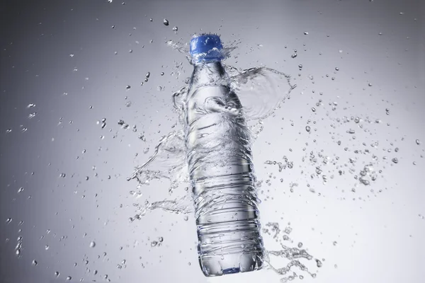 Bottiglia e spruzzi d'acqua isolati su uno sfondo bianco — Foto Stock