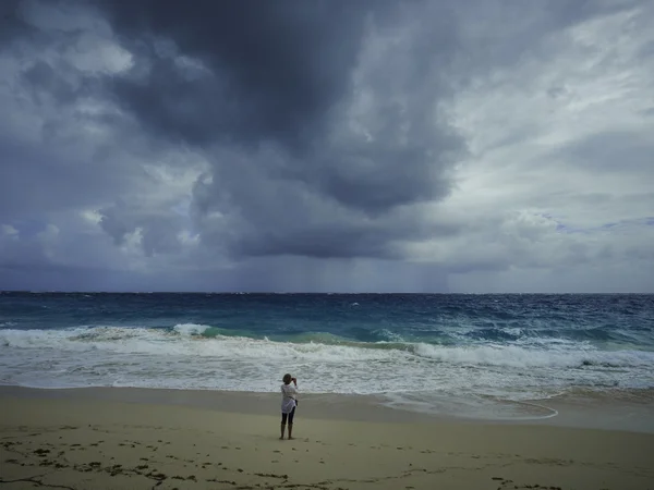 Vrouw op een zandstrand op een bewolkte dag — Stockfoto