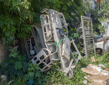 Terk edilmiş yatak ve tıbbi malzemeler, unutulmuş hastane çöp ve bitkilerle çevrili.