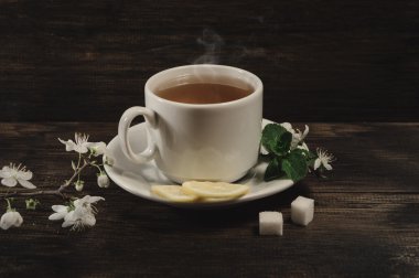 Fincan çay ve bahar eski ahşap zemin üzerine kayısı çiçeği