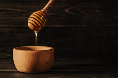 Ahşap arka plan üzerinde ahşap bal ayı üzerinden damlayan bal