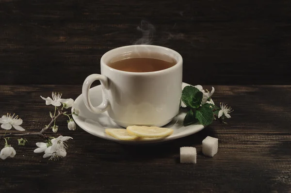 Fincan çay ve bahar eski ahşap zemin üzerine kayısı çiçeği