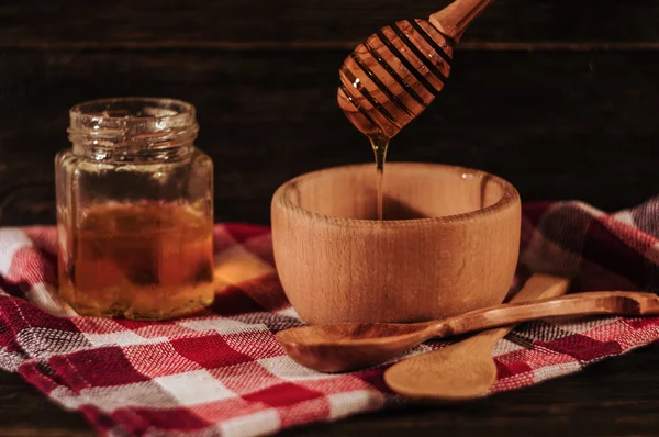 Ahşap arka plan üzerinde ahşap bal ayı üzerinden damlayan bal