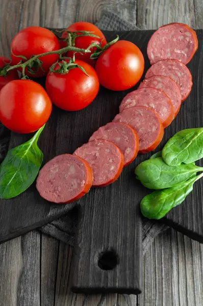 Domatesli füme sosis ve ahşap doğrama tahtasında fesleğen.