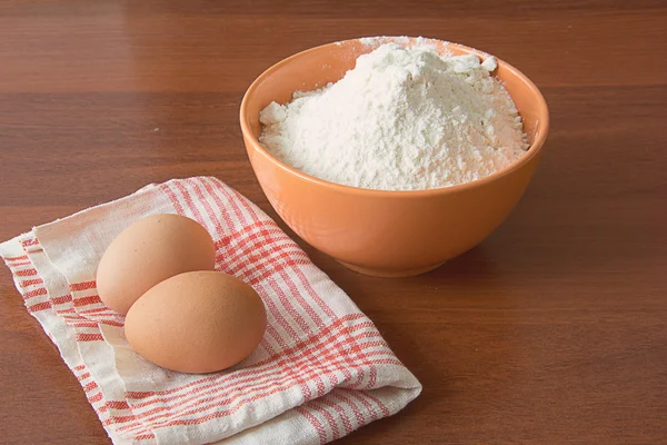 Eggs on a dishcloth and flour in a bowl — Stock Photo, Image