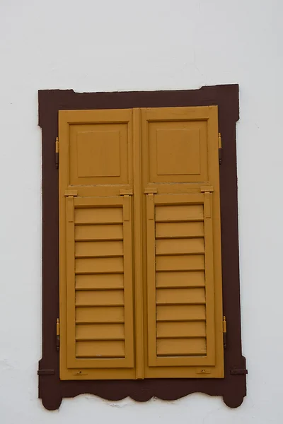 Gesloten gele houten venster luiken — Stockfoto