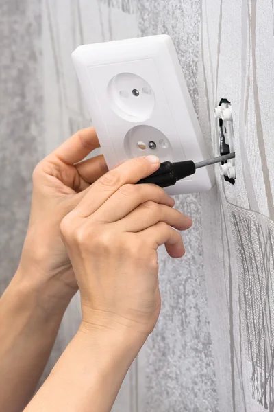 hands with screwdriver installing a wall power socket