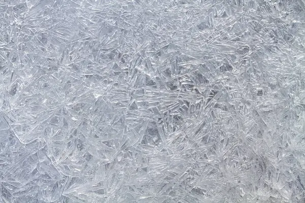 A patterned surface of ice, consisting of melted and then frozen ice needles. Abstract winter background for Christmas.