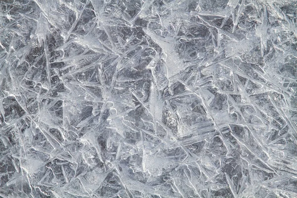 The ice crystals froze into the icy surface and formed a bizarre pattern. Close-up. Abstract winter background for Christmas and New Year.