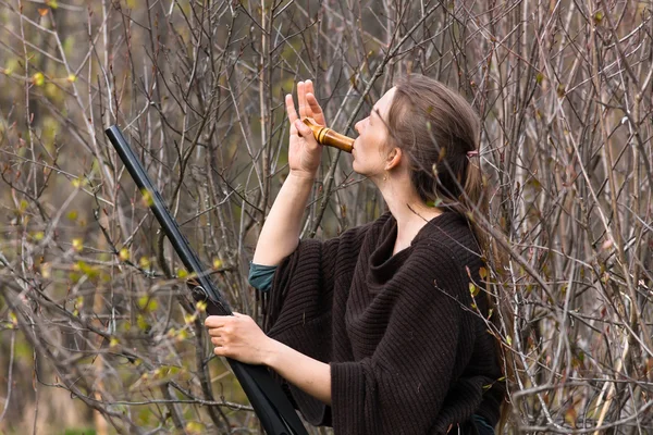 woman hunter in shrubs with a wooden duck call