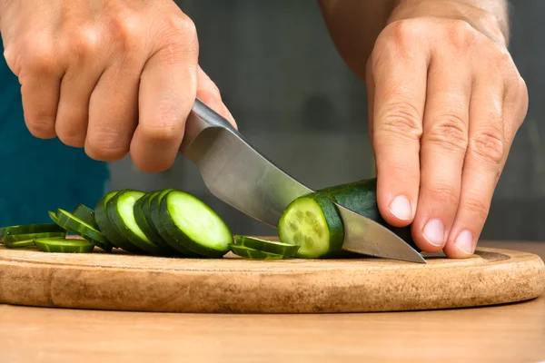 Manos rebanando pepino en la tabla de cortar — Foto de Stock