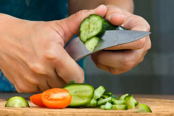 Hands of woman preparing salad from cucumbers and tomatoes Stock Picture