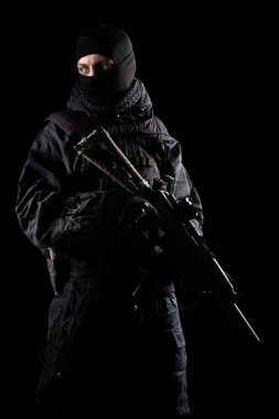 Siyah özel kuvvetler üniformalı silahlı bir erkek. Stüdyoda çekilmiş. Siyah arkaplanda kırpma yolu ile izole edildi