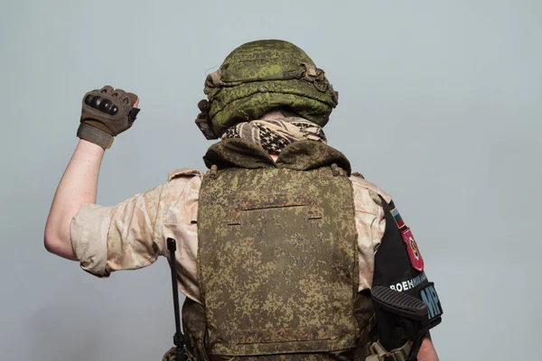 Russian military police soldier in desert uniform. Patch on the shoulder flag of Russia, arms of Russian army and the inscription Military Police in Russian. Shot in studio on a grey background.