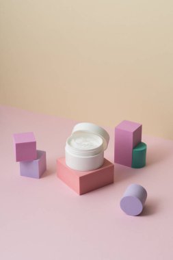 Bej ve pembe arka planda beyaz kozmetik krem kavanozu. (Güzellik konsepti posteri, ters görüntü)