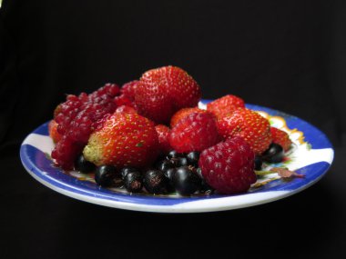 Siyah bir zemin üzerine plaka üzerinde çeşitli meyveler.