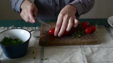 Tahtada kiraz domateslerini yarıya indiren adam.