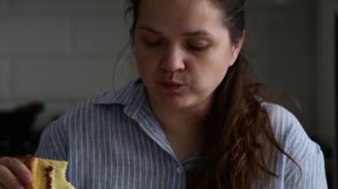 Ev mutfağında peynirli ve mantarlı klasik Napoli pizzası yiyen bir kadın. Rahat bir yemek sırasında geleneksel İtalyan yemeklerini gösteren sıradan bir yemek sahnesi..