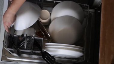 Üst taraf, ellerinde çatal bıçak, kaşık ve bıçakları kaldıran bir çatal bıçak kabıyla el ele tutuşuyor. Üst mutfak rutini evde sofra takımlarının düzenli düzenlendiğini gösteriyor.