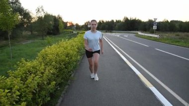 Genç bir kadın gün batımında koşmaya ve hızlanmaya başlıyor. Yavaş çekim güçlü ilk adımları ve dinamik kentsel zindelik atmosferini yakalar. Yeni başlangıçlar, motivasyon ve performans kavramları için ideal.