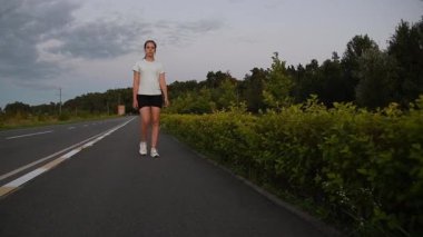 Genç bir kadın gün batımında kameraya doğru hızla yürüyordu. Düşük yerden yavaş çekimde çekilmişti. Ön izleme çekimi geçiş, güç ve dinamik kentsel zindelik atmosferini vurgular. Motivasyon ve ilerleme için ideal.