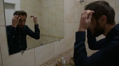 Adam banyodaki aynada kendine bakarken gömleğini düzeltiyor ve saçını düzeltiyor, sonra da odadan çıkıyor. Güne başlamadan önce kişisel bakım ve hazırlıkları gösteren sabah rutin sahnesi.