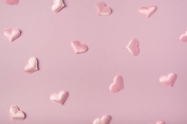 Şenlikli pembe arka plan. Pembe arka planda pembe saten kalpler. Sevgililer Günü. Düğün için. Doğum günü. Düz yatış, üst görünüm.