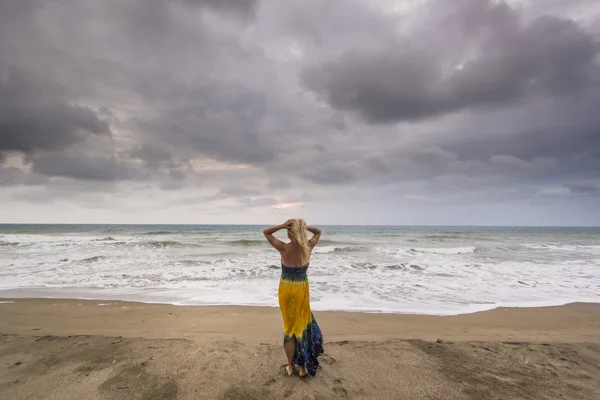 Meisje permanent op een strand zand oceaan in bewolkt weer — Stockfoto