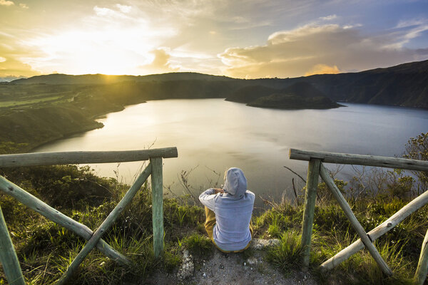 girl sitting on a edge of crater with lake inside