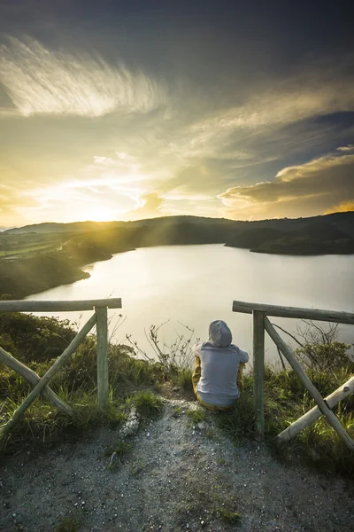 Meisje zittend op een rand van de krater met meer binnen — Stockfoto