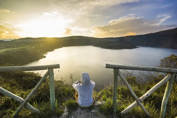 Girl sitting on a edge of crater with lake inside — Stock Photo, Image