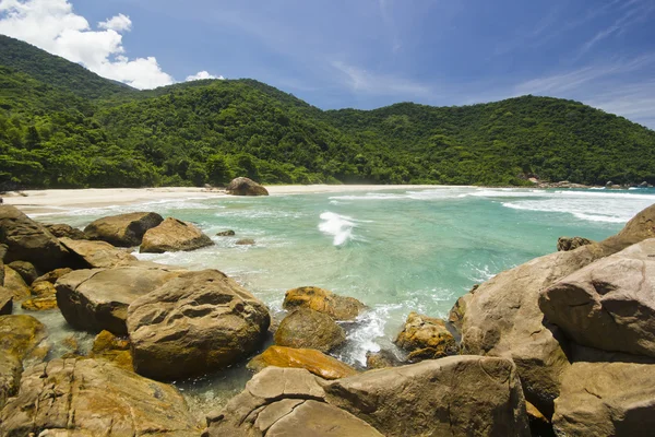 Belle plage tropicale avec de l'eau verte et des pierres au premier plan — Photo