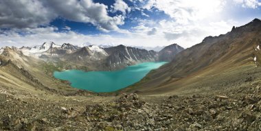 gün batımında yüksek tepeler tarafından çevrili mavi dağ gölü