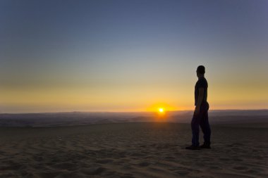 gün batımında ayakta adam çölde