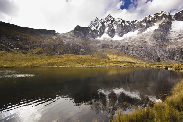 Lago buio ai piedi della montagna innevata all'alba — Foto Stock