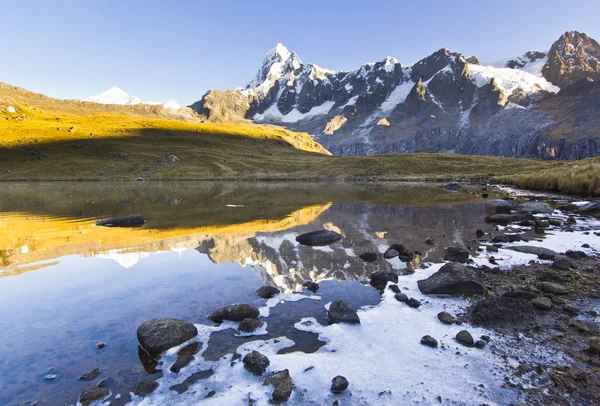 Lago tranquilo a pie de montaña cubierta de nieve al amanecer — Foto de Stock
