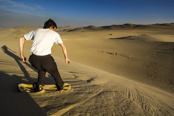 Homme sur le bac à sable dans le désert au coucher du soleil — Photo