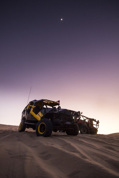 buggy on dunes at sunset