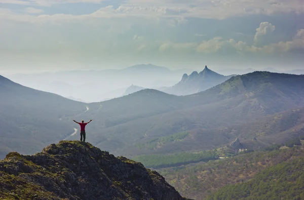 Homme debout sur une falaise dans les montagnes avec les mains en l'air — Photo