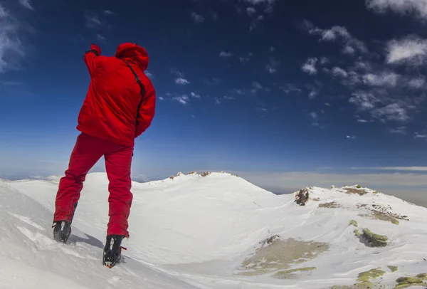 Homem de pé em uma encosta de neve nas montanhas — Fotografia de Stock