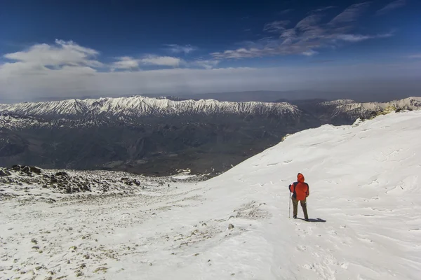 Homem de pé na encosta da montanha de neve em casaco vermelho — Fotografia de Stock