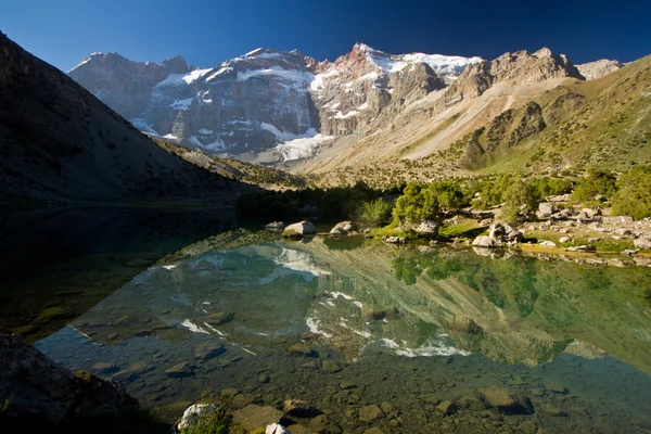Blue mountain lake reflects high rocks — Stock Photo, Image