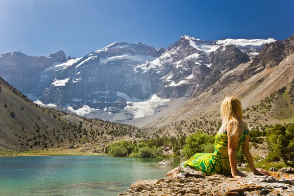Dívka sedící na břehu jezera modré hory — Stock fotografie